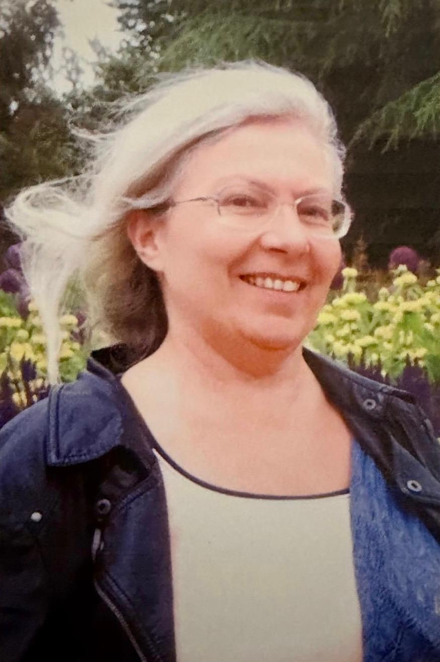 Teresa smiling in a garden, hair blowing in the wind